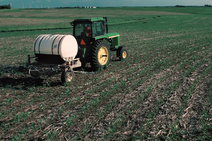 View of nitrogen fertilizer being applied to growing corn (maize) in a contoured, no-tilled field in Hardin County, Iowa