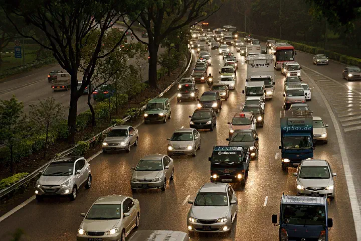 New cars, electric trucks and older vehicles in a traffic jam in the rain.