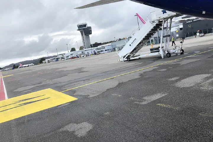 A parked Wizz Air A321 at stand 11, with the terminal building and air traffic control tower beyond.