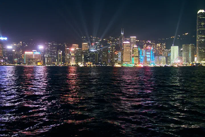 Victoria Harbour and the Hong Kong Island skyline at night, with the Symphony of Lights laser show in progress