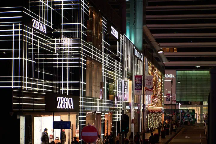 Luxury storefronts including Zegna and Tiffany & Co. on a Hong Kong shopping street at night.