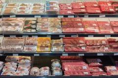 Trays of pork, beef and chicken laid out under the lights of a supermarket meat counter