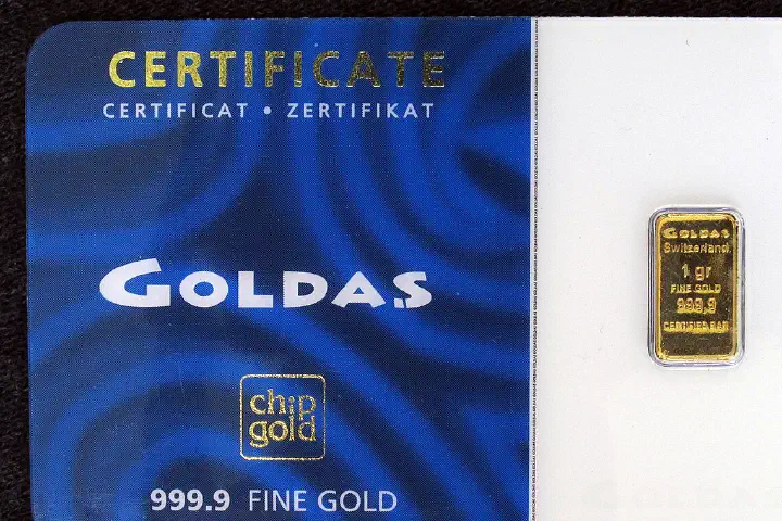 A gold bullion bar with an assay card.