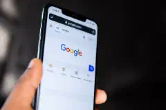 A person holding a phone showing the Google homepage.