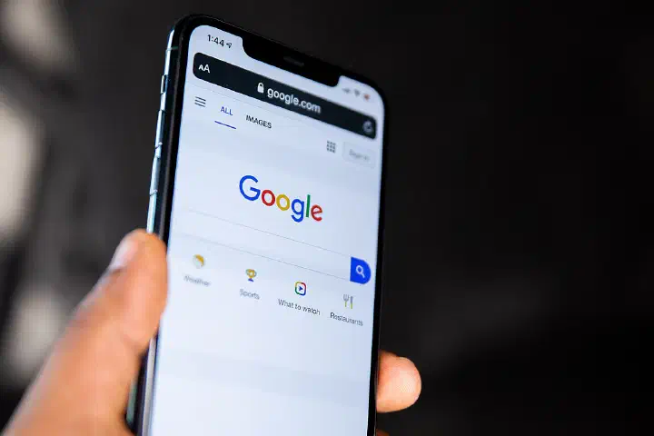 A person holding a phone showing the Google homepage.