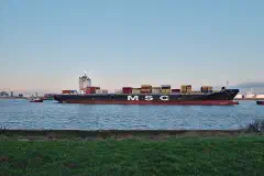 The container ship MSC Carmen is towed along the Scheldt toward the Port of Antwerp, seen from Doel, Belgium.