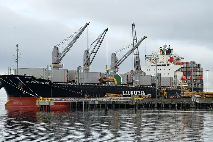 The Lauritzen bulk carrier Happiness Bulker loading raw logs at the dock in Port Angeles Harbor, Washington.