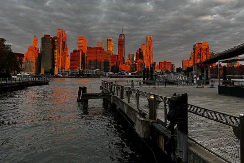 The Manhattan Financial District skyline under an orange sky, seen from the Fulton Ferry Landing.